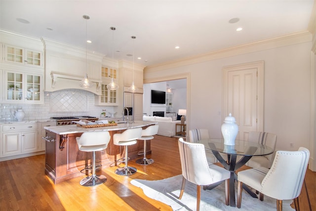 kitchen with a breakfast bar, light wood-type flooring, a kitchen island with sink, and decorative backsplash