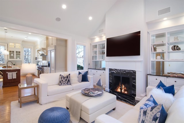 living area with plenty of natural light, light wood-style flooring, a premium fireplace, and visible vents