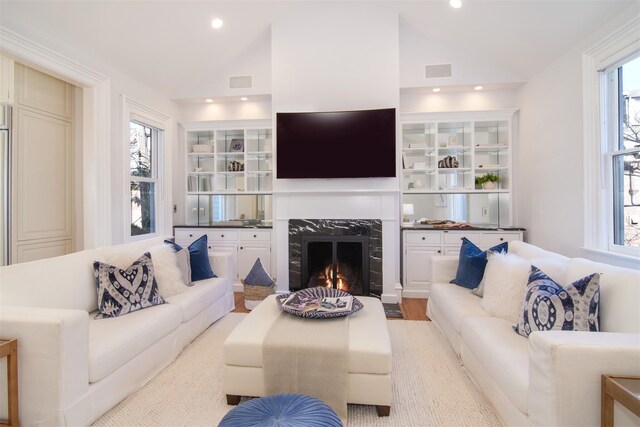 living area with lofted ceiling, a fireplace, built in features, and recessed lighting