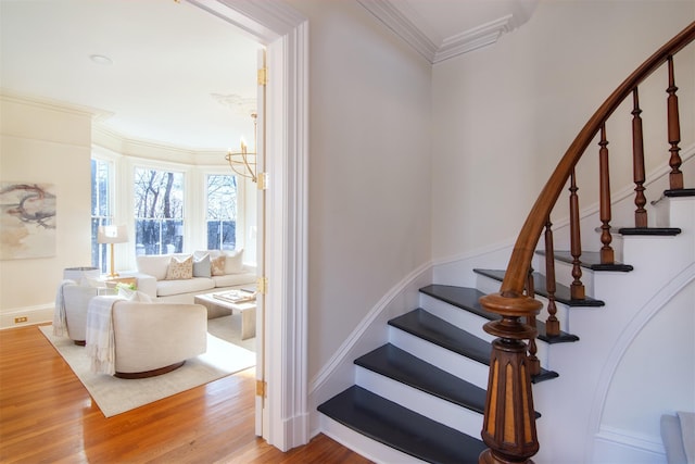 stairway with ornamental molding, a chandelier, baseboards, and wood finished floors