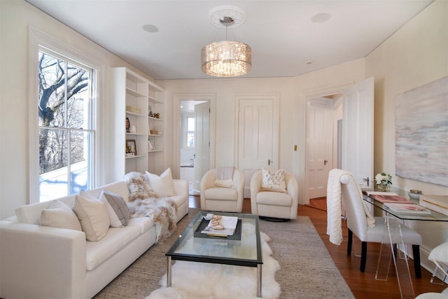 living area with built in features, a chandelier, and wood finished floors