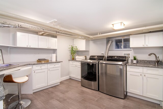 kitchen with washing machine and clothes dryer, a sink, and white cabinetry