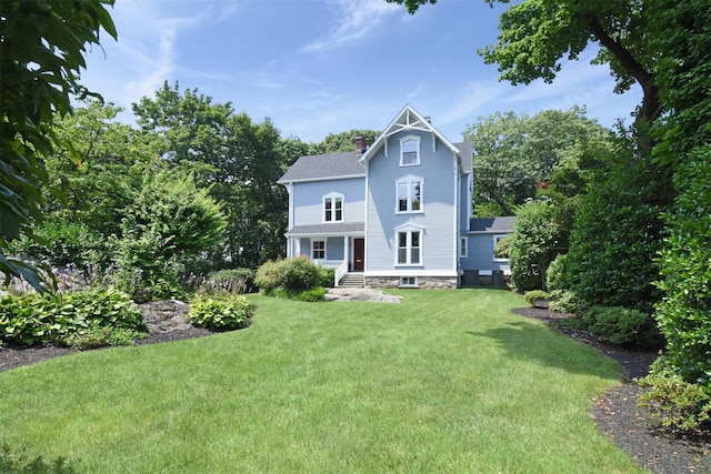 back of house featuring a chimney and a yard