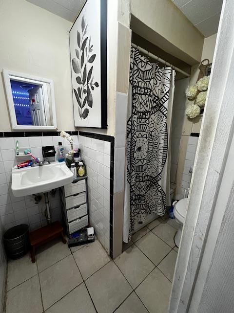 full bathroom with tile patterned flooring, a sink, and tile walls