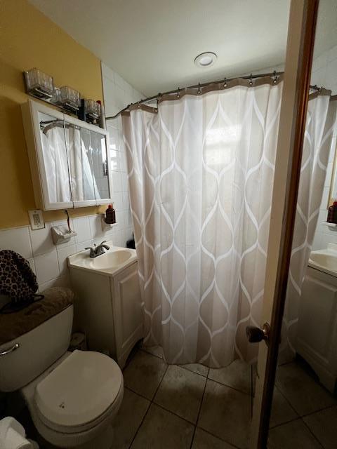 full bathroom featuring tile walls, toilet, vanity, a shower with curtain, and tile patterned floors