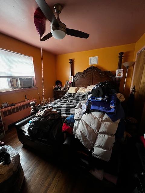 bedroom with radiator, ceiling fan, and wood finished floors