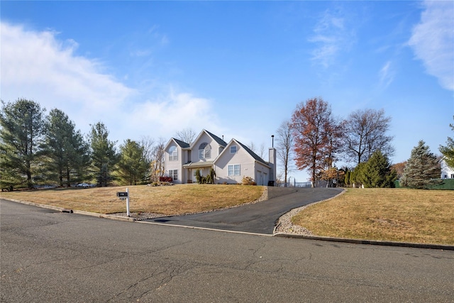 view of front of property featuring aphalt driveway, a front yard, and a garage