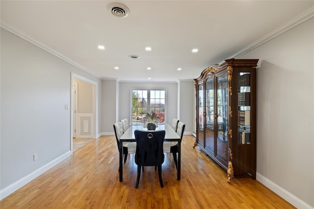 dining area featuring light wood-style floors, visible vents, and crown molding