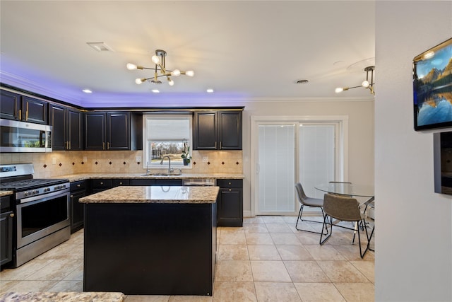 kitchen featuring a notable chandelier, tasteful backsplash, appliances with stainless steel finishes, a sink, and light stone countertops