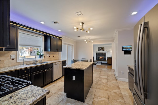 kitchen with stainless steel appliances, a sink, a center island, decorative backsplash, and crown molding