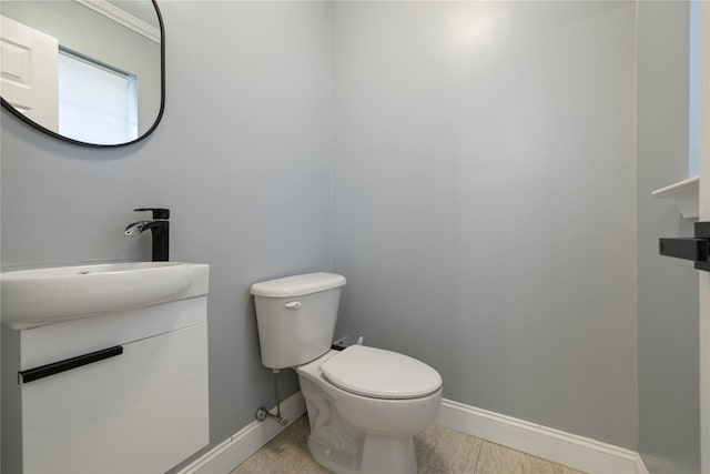 half bathroom featuring vanity, toilet, and baseboards