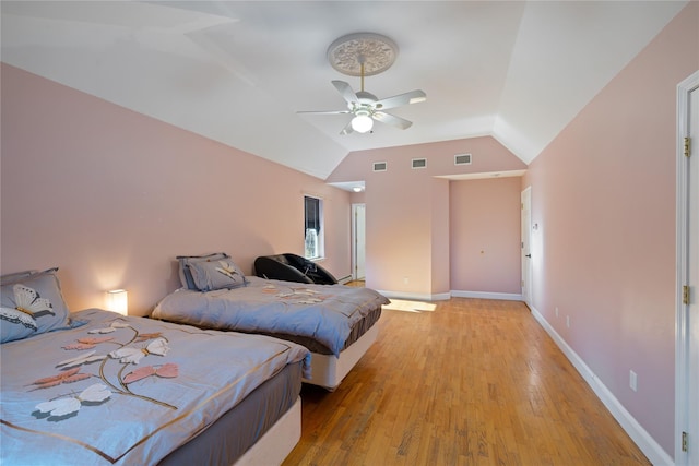 bedroom with lofted ceiling, light wood-style floors, baseboards, and visible vents