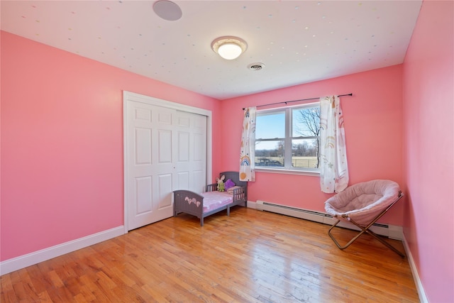 sitting room with baseboards, visible vents, baseboard heating, and wood finished floors