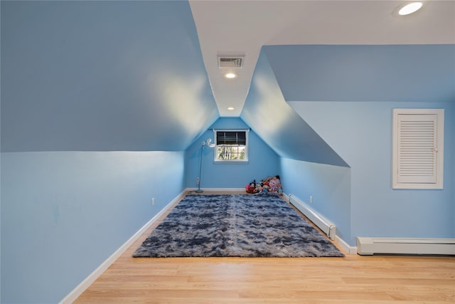 bonus room with a baseboard heating unit, lofted ceiling, visible vents, and wood finished floors