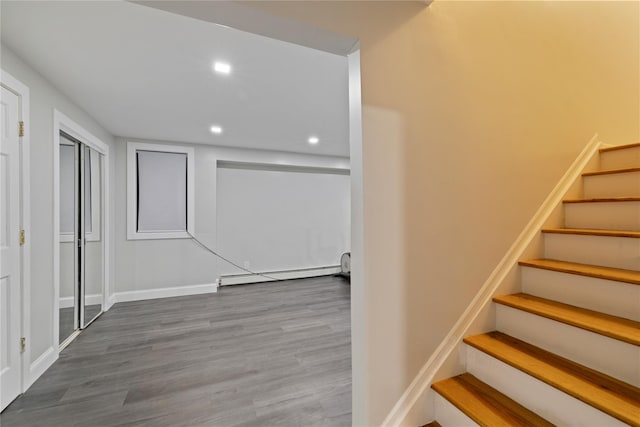 stairway with baseboards, a baseboard radiator, wood finished floors, and recessed lighting