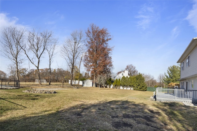 view of yard featuring a deck, an outdoor structure, and fence