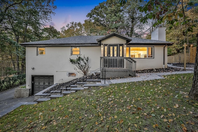 view of front of home featuring a chimney, stucco siding, fence, a garage, and a front lawn