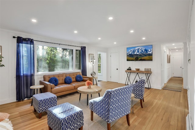 living area with a baseboard heating unit, light wood-style flooring, and recessed lighting