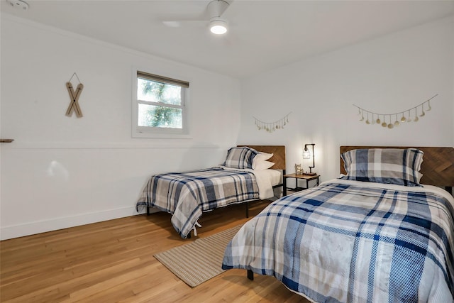 bedroom with a ceiling fan, crown molding, baseboards, and wood finished floors