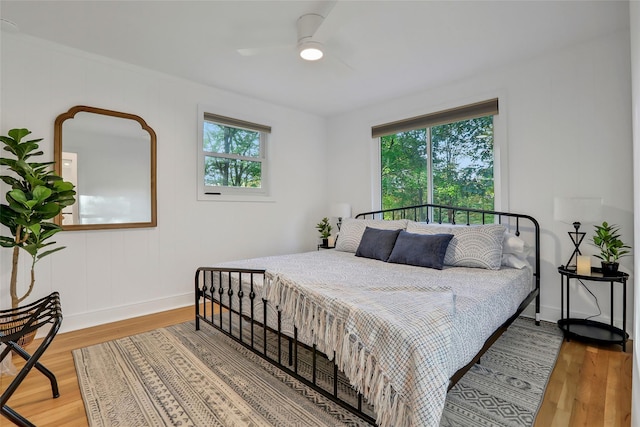 bedroom with multiple windows, light wood-style flooring, and baseboards