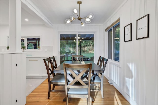 dining space featuring light wood finished floors, a decorative wall, and a notable chandelier