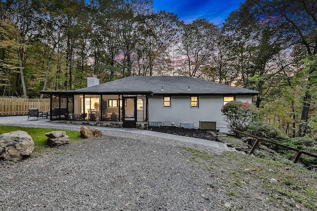 rear view of house featuring a patio, a chimney, stucco siding, fence, and driveway