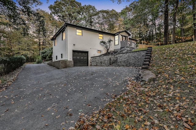 view of property exterior with a garage, aphalt driveway, stairway, and stucco siding