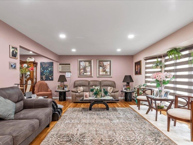 living room with a wall unit AC, light wood finished floors, and recessed lighting