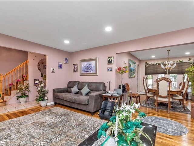 living room featuring an inviting chandelier, stairs, wood finished floors, and recessed lighting