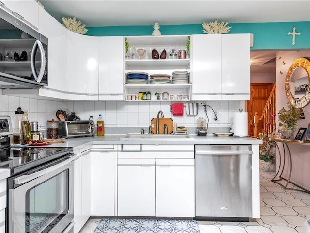 kitchen with stainless steel appliances, a sink, backsplash, and open shelves