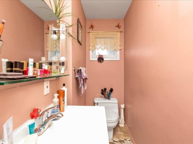 bathroom featuring baseboards, a sink, and toilet