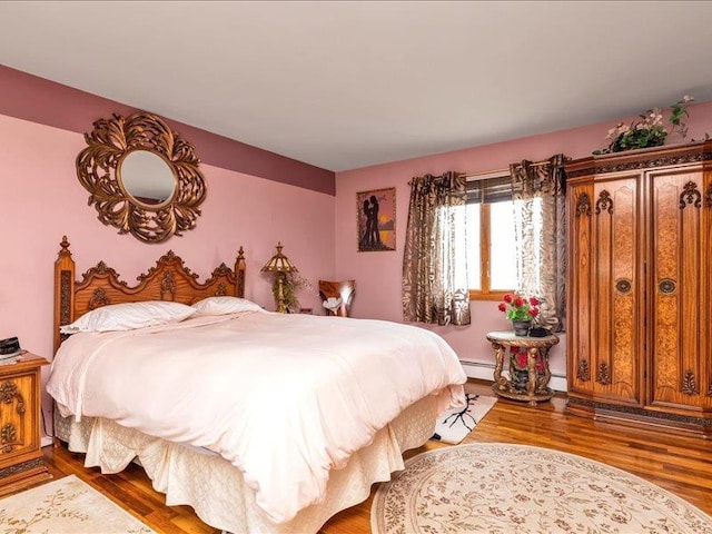 bedroom with a baseboard heating unit, baseboard heating, and wood finished floors