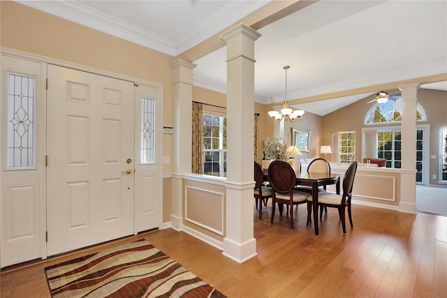 foyer entrance with ornate columns, crown molding, a chandelier, and wood finished floors