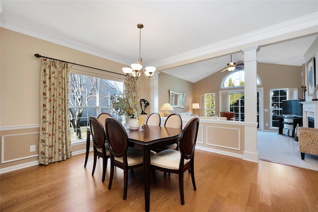 dining space with light wood-type flooring, vaulted ceiling, plenty of natural light, and a decorative wall