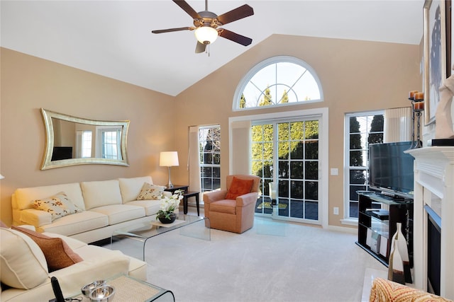 carpeted living area featuring high vaulted ceiling, a fireplace, and a ceiling fan