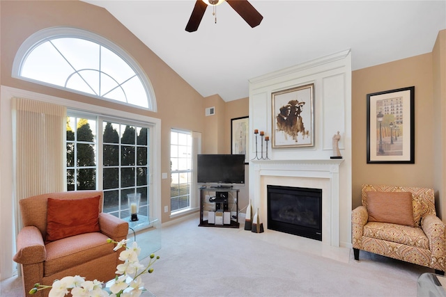 carpeted living area with high vaulted ceiling, a fireplace with flush hearth, visible vents, and ceiling fan