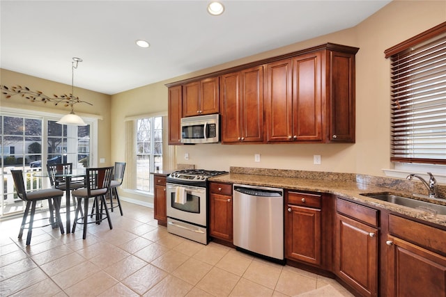 kitchen with light stone counters, decorative light fixtures, stainless steel appliances, a sink, and recessed lighting