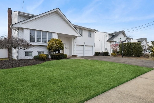 view of front of home with a front lawn, a garage, driveway, and a chimney