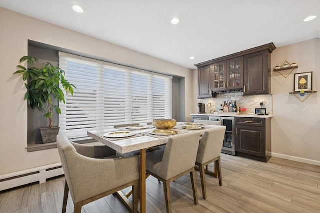 dining room with baseboards, light wood finished floors, recessed lighting, a bar, and wine cooler