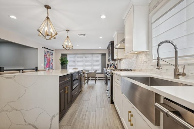 kitchen with decorative light fixtures, tasteful backsplash, stainless steel appliances, white cabinets, and a chandelier