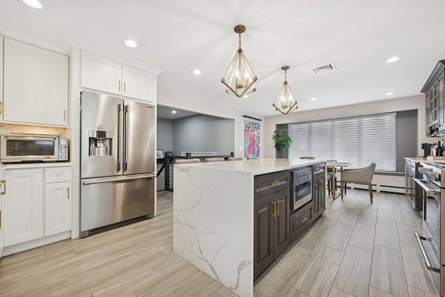 kitchen featuring light stone countertops, visible vents, white cabinets, appliances with stainless steel finishes, and a center island