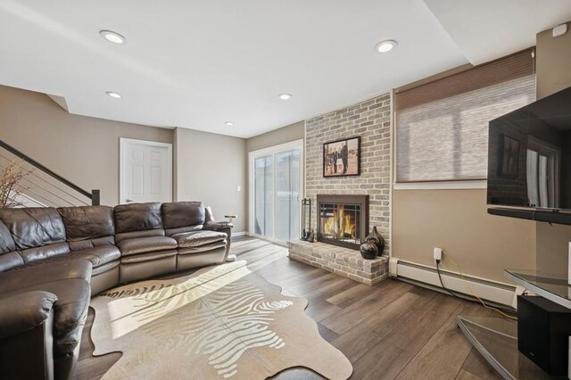 living area with recessed lighting, a brick fireplace, wood finished floors, and a baseboard radiator