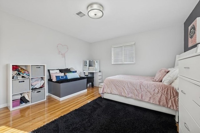 bedroom with visible vents, baseboards, and wood finished floors