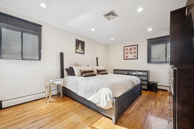 bedroom with light wood-type flooring, visible vents, baseboard heating, and recessed lighting