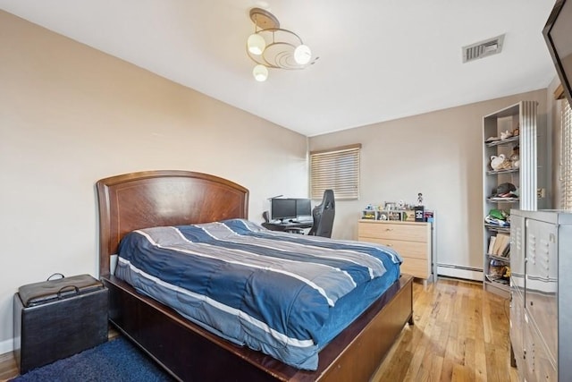 bedroom featuring visible vents, light wood-style floors, and a baseboard radiator