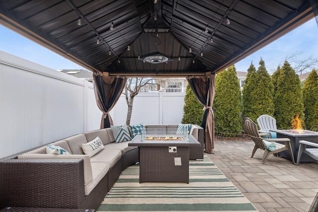 view of patio / terrace with a gazebo, an outdoor living space with a fire pit, and fence