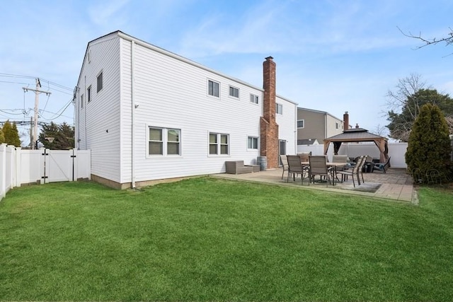 back of house featuring a patio area, a gazebo, a yard, and a gate