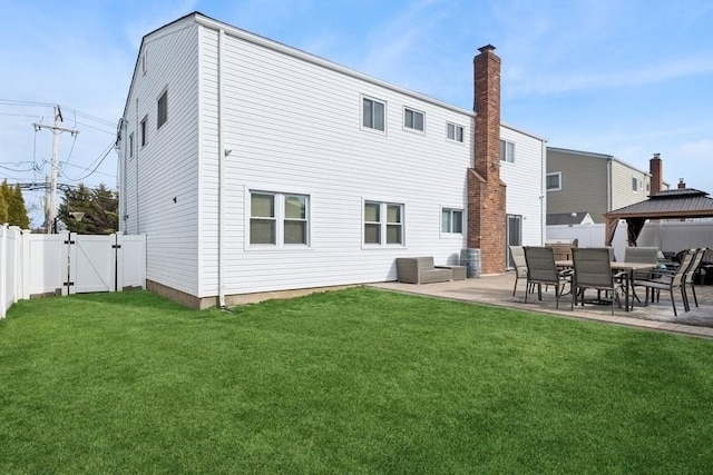 rear view of house with a patio, a gate, a fenced backyard, and a yard