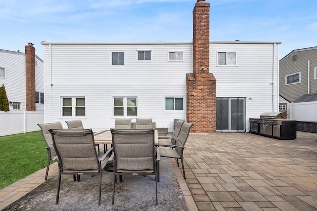 back of property with outdoor dining area, a patio area, and fence