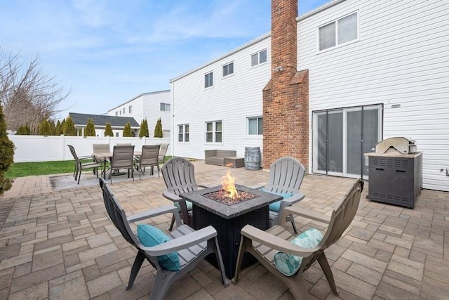 view of patio with an outdoor fire pit, outdoor dining area, and fence